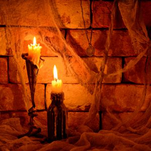 Halloween still life with two burning candles on brick wall