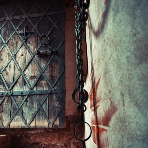Fragment of medieval dungeon prison. Focus on ancient door.